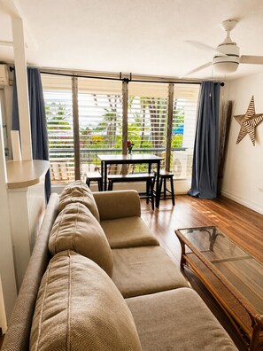 A living room with a sofa, a glass coffee table, and a dining area with a table and chairs. - Make Memories in Paradise at Long Reef (Christiansted)