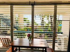 A dining area with a table and chairs, a vase with flowers, and a view through a window with horizontal blinds. - Make Memories in Paradise at Long Reef (Christiansted)