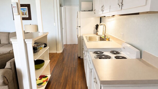 Una cocina moderna con armarios blancos, horno empotrado y pileta de acero inoxidable.