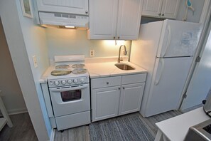 A compact kitchen with a stove, oven, sink, and a refrigerator. - Guest House 207 - Walk to Garden City Beach (Garden City)