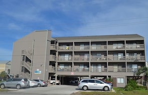 Un edificio de varios pisos con un estacionamiento al frente.