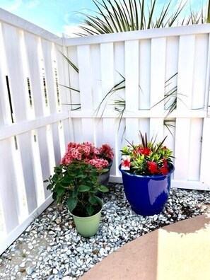 A white wooden fence with potted plants on a gravel surface. - Guest House 207 - Walk to Garden City Beach (Garden City)