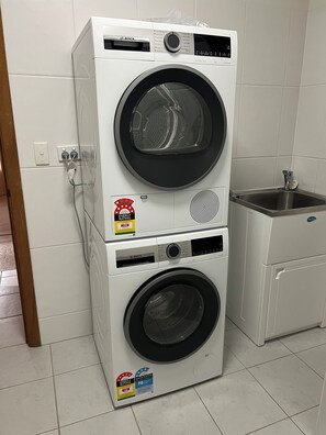 A stacked washer and dryer unit with energy and water efficiency ratings. - Carrickalinga Beach House (Carrickalinga)