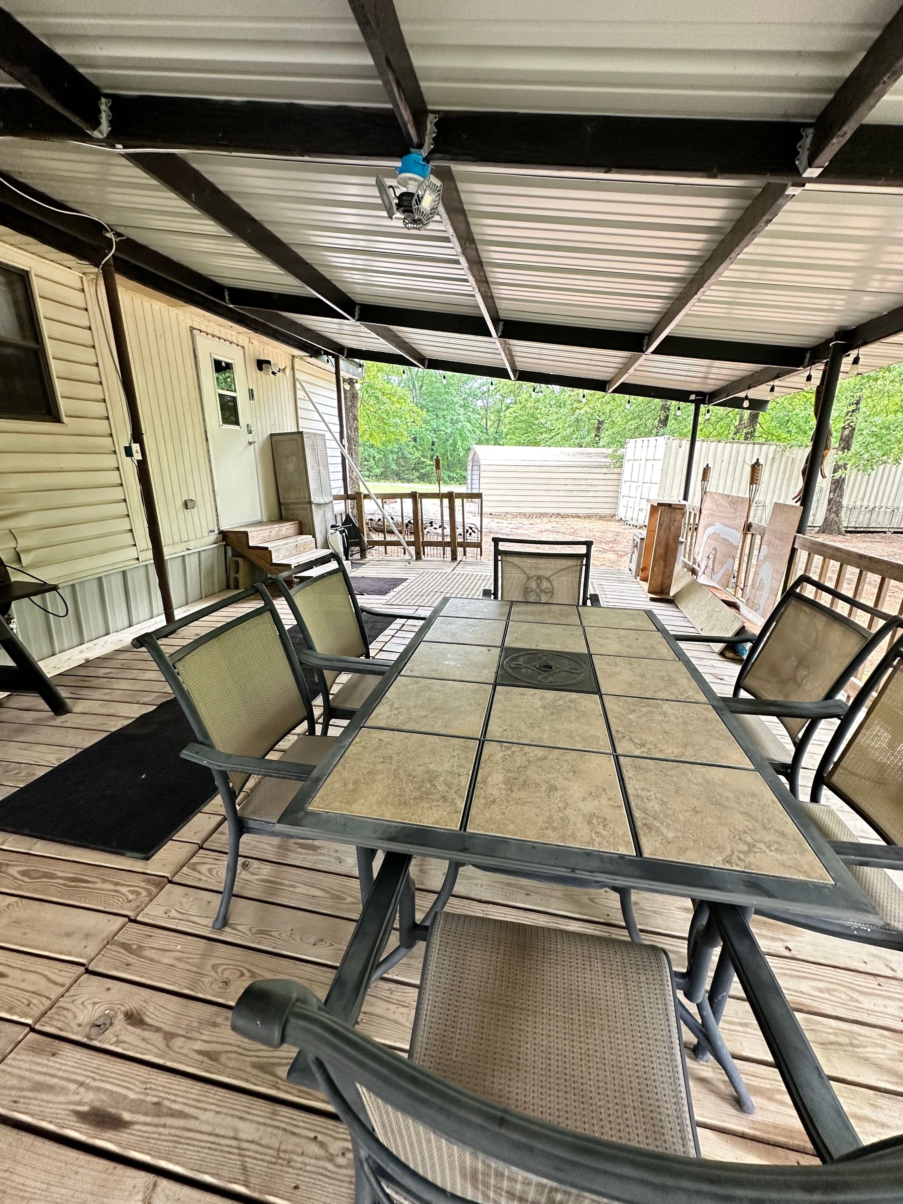An outdoor patio with a covered seating area, a table, and chairs.
