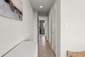 A hallway with a tiled floor, white walls, and a door at the end. - New! Gulf Front! Pool, Hot Tub, Steps to the Beach, Beach Manor 210 (Miramar Beach)