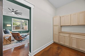 Eine moderne Küche mit Holzausbau, einem Deckenventilator und Blick auf den Garten durch ein Fenster.