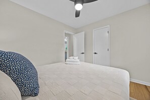 Ein Schlafzimmer mit Bett, Deckenventilator und Tür.