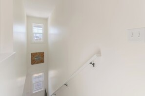 Ein helles Interieur mit Treppe, einem an der Wand montierten Lichtschalter und einem gerahmten Bild.