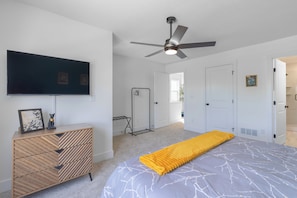 Ein Schlafzimmer mit Bett, Fernseher, Deckenventilator und begehbarer Kleiderschrank.