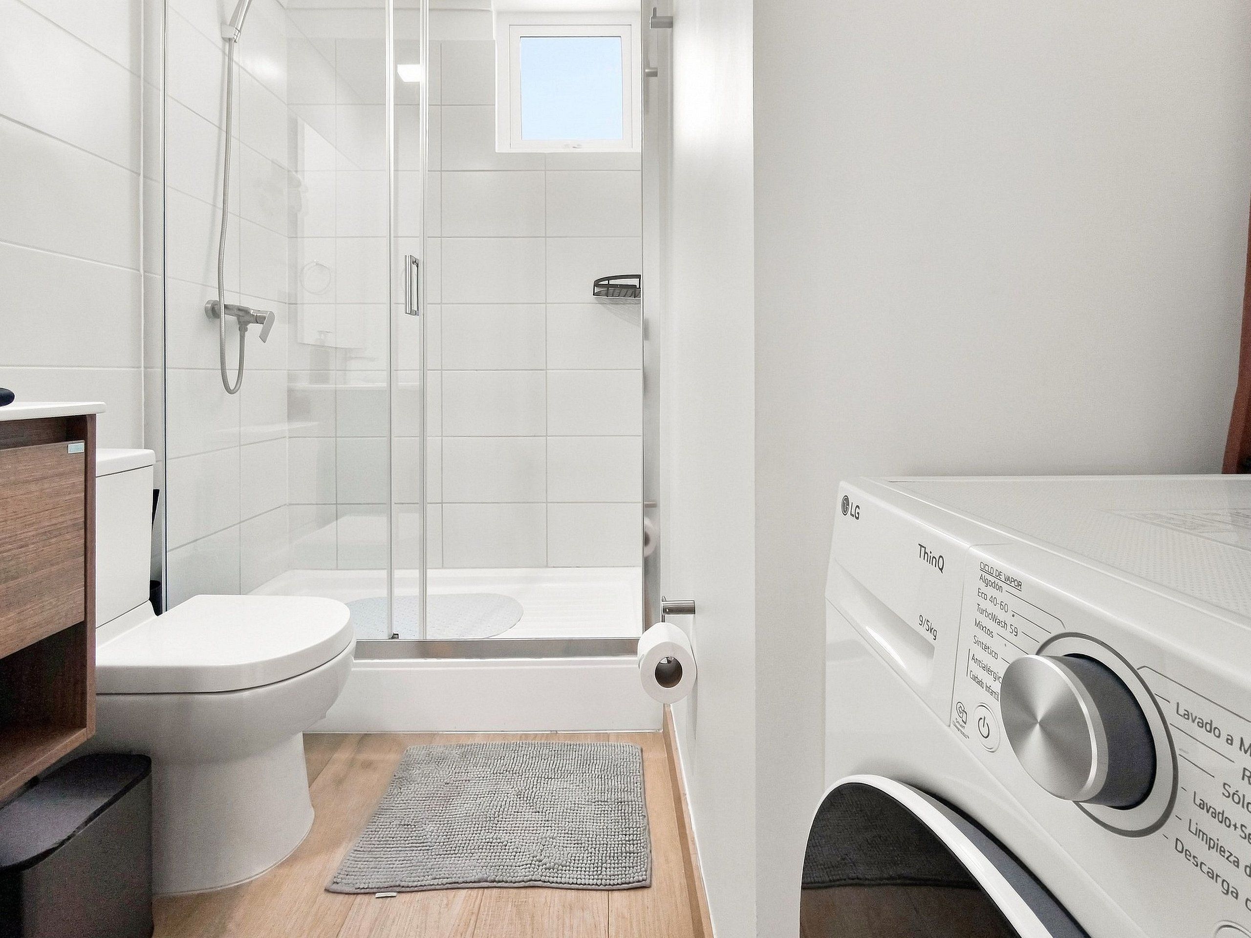 A modern bathroom with a toilet, shower, and a washing machine.