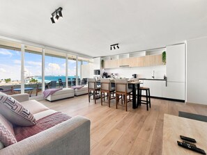 Un espacio moderno con comedor, cocina y ventanas amplias con vistas al mar.