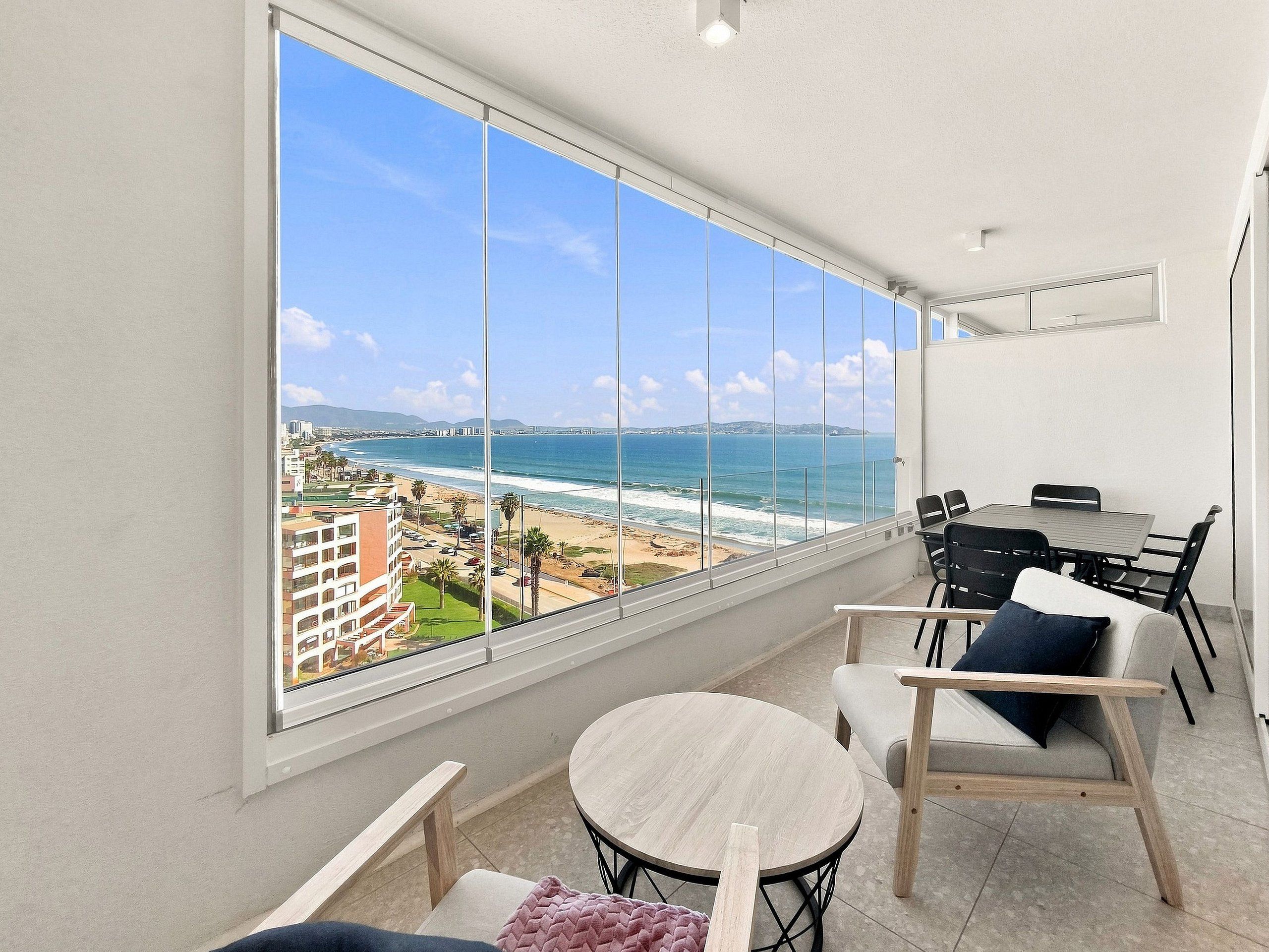 Un balcon avec vue sur la plage et l’océan, aménagé avec une table ronde et des chaises.