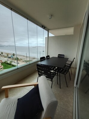 A balcony with a table and chairs, overlooking a beach and ocean. - Oceana Suites Playa Serena (Coquimbo)