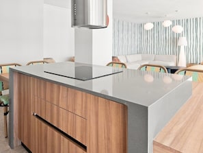 A modern kitchen with a central island, wooden cabinetry, and a stainless steel range hood. - Oceana Suites Playa Serena (Coquimbo)
