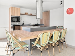 A modern kitchen with a central island, built-in appliances, and a dining area with wicker chairs. - Oceana Suites Playa Serena (Coquimbo)