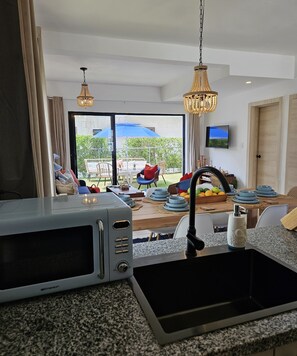 A modern kitchen with a built-in microwave, a sink, and a dining area with a table set for four. - 2-bedroom townhome in peaceful Punta Cana with AC comfort (Punta Cana)