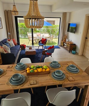A dining area with a wooden table set for four, surrounded by white chairs. - 2-bedroom townhome in peaceful Punta Cana with AC comfort (Punta Cana)