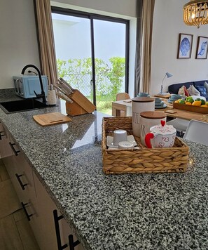 Eine Küche mit Granit-Arbeitsplatten, einem Toaster, einer Kaffeemaschine und einem Korbkorb mit Küchenutensilien.