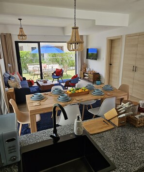 A modern kitchen with a dining area, large windows, and a view of the outdoors. - 2-bedroom townhome in peaceful Punta Cana with AC comfort (Punta Cana)