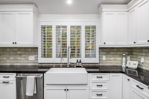 A modern kitchen with white cabinets, a stainless steel sink, and a window with a view of greenery. - Spacious 4-bedroom house in enchanting Beverly Hills (Beverly Hills)