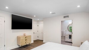 Ein Schlafzimmer mit einem Bett, einem Schrank, einem Fernseher und einem durch eine offene Tür einsehbarer Badezimmer.
