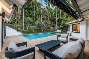 A poolside area with a pool, lounge chairs, and a small table. - Spacious 4-bedroom house in enchanting Beverly Hills (Beverly Hills)