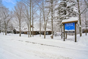 A snow-covered landscape with a sign for the Sports Center and a wooden cabin. - Ski-back hotel room with mountain views, pool, and hot tub. (Killington)