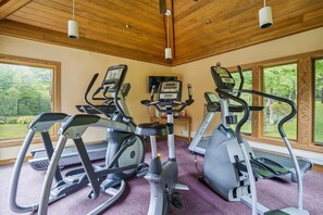 A gym with three elliptical machines, a treadmill, and a stationary bike. - Ski-back hotel room with mountain views, pool, and hot tub. (Killington)