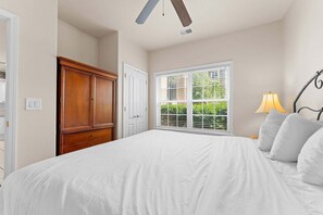 A bedroom with a large bed, a wardrobe, a window with blinds, and a lamp. - French Quarter Resort | 2 King Suites | Pet Friendly (Branson)