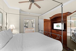 A bedroom with a four-poster bed, a ceiling fan, a television, and a wooden wardrobe. - Relax at French Quarter | 2BR Condo with Balcony (Branson)