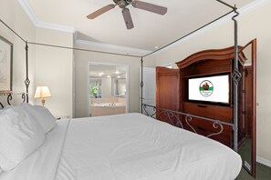A hotel room with a bed, a television, a ceiling fan, and a bathroom visible through an open door. - Branson 2BR Condo | Pool • Hot Tub • Balcony (Branson)