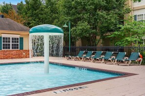 Ein Pool mit Wasserspiel, umgeben von Liegestühlen und einer Ziegelmauer.