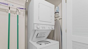 Máquina de lavar frontal com painel de controle e um varal em cima.
