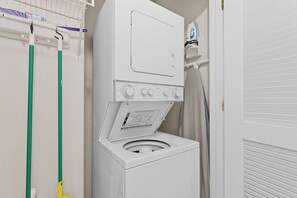 Eine Waschmaschine mit Frontlader, Bedienfeld und Kleiderstange darüber.