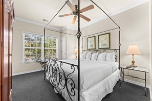 A four-poster canopy bed with a ceiling fan, a bedside table with a lamp, and framed artwork on the wall. - Family-Friendly 2BR Near Silver Dollar City (Branson)