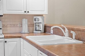 Eine Küche mit weißen Schränken, einer Kaffeemaschine und einem Waschbecken mit modernem Wasserhahn.
