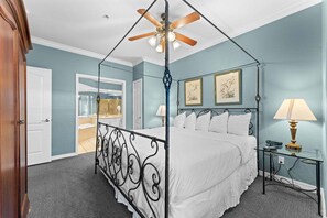 A bedroom with a four-poster bed, a ceiling fan, and a nightstand with a lamp. - Branson Condo | 2 King Suites | Great Location (Branson)