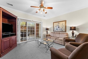 A living room with a television, sofa, armchairs, a coffee table, and a ceiling fan. - Branson Condo | 2 King Suites | Great Location (Branson)