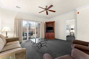 Ein Hotelzimmer mit einer Sitzecke, einem Fernseher und einem Deckenventilator.