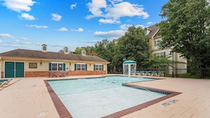 A swimming pool with a fountain, a brick patio, and a building with a green door. - French Quarter Resort | Close to Shows & Shopping (Branson)