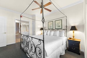 A four-poster bed with a canopy, a bedside table with a lamp, and framed artwork on the wall. - French Quarter Resort | Close to Shows & Shopping (Branson)