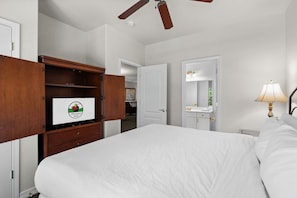 A bedroom with a large bed, a wardrobe, a vanity with a mirror, and a ceiling fan. - Branson Family Getaway | 2BR Resort Condo | Pool (Branson)