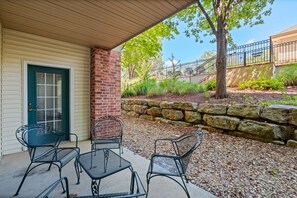 A covered patio with outdoor seating and a stone wall. - Prime Branson Getaway | Near the Strip & Shows (Branson)