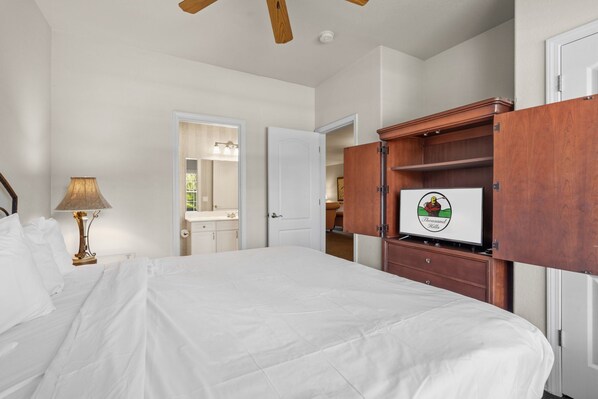 Een slaapkamer met een bed, een nachtkastje met een lamp, een kledingkast en een deur naar een andere kamer.