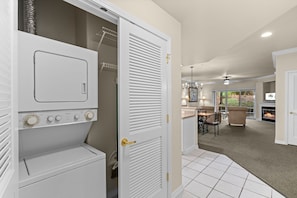 A laundry room with a washer and dryer, a door leading to a dining area with a fireplace, and a ceiling fan. - French Quarter Resort | The Perfect Branson Location (Branson)