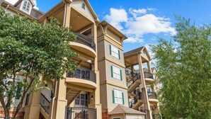 A multi-story residential building with balconies, a brick facade, and a clear blue sky. - Branson Strip Condo | Pool • Hot Tub • 2 Kings (Branson)