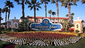 Letrero del Westgate Lakes Resort & Spa con palmeras y un jardín de flores.