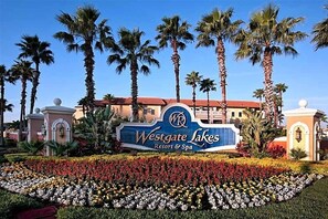 A Westgate Lakes Resort & Spa sign with palm trees and a flower bed. - Westgate Lakes Resort & Spa Universal Studios Area (Orlando)
