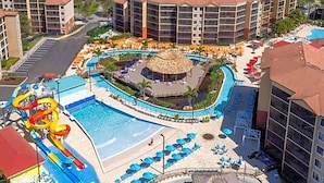 Un resort con una piscina grande, toboganes acuáticos y una estructura de techo de paja.