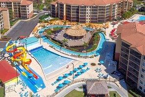 A resort with a large pool, water slides, and a thatched-roof structure. - Westgate Lakes Resort & Spa Universal Studios Area (Orlando)